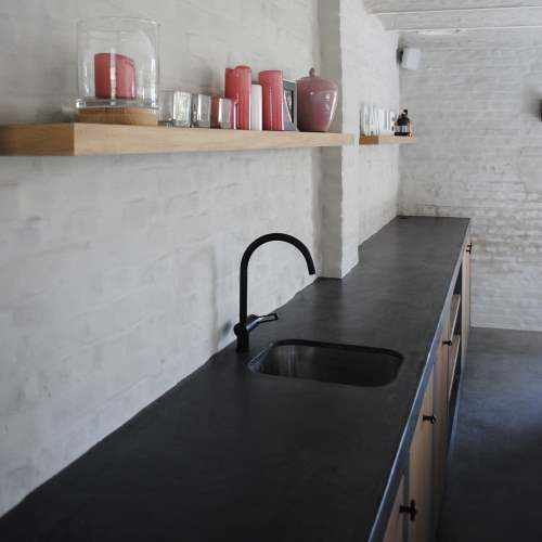 a kitchen with black counter tops and white brick walls