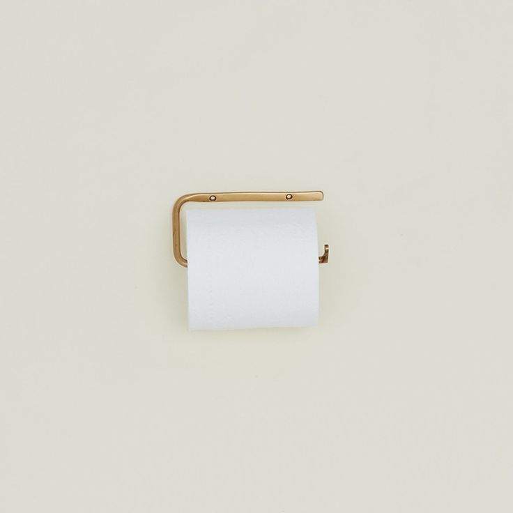 a roll of toilet paper sitting on top of a white wall next to a gold handle