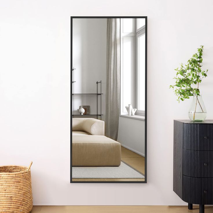 a living room with a large mirror on the wall next to a basket and plant