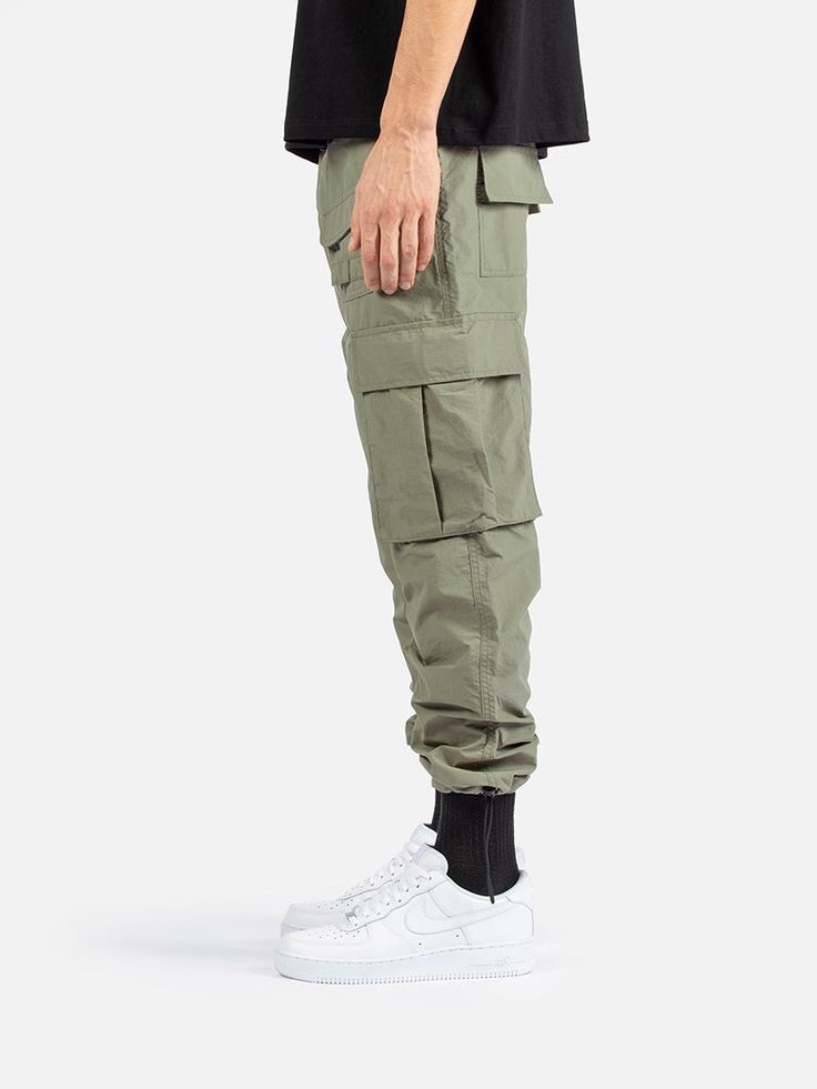 Combat Style Cargo Pants With Functional Pockets For Outdoor, Combat Cargo Pants With Functional Pockets For Outdoor, Khaki Utility Cargo Jeans With Elastic Waistband, Utility Cargo Pants With Elastic Waistband In Khaki, Utility Khaki Cargo Pants With Elastic Waistband, Military Style Cotton Cargo Pants With Elastic Waistband, Military Cotton Cargo Pants With Elastic Waistband, Military Cargo Jeans For Streetwear, Military Style Relaxed Fit Cargo Pants With Elastic Waistband