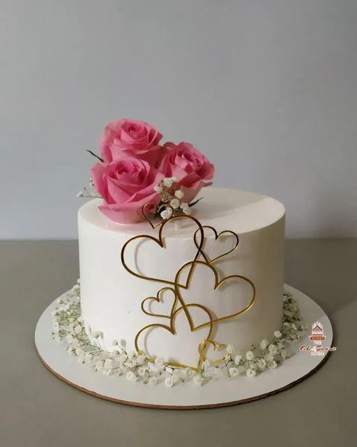 a white and gold cake with pink roses on top