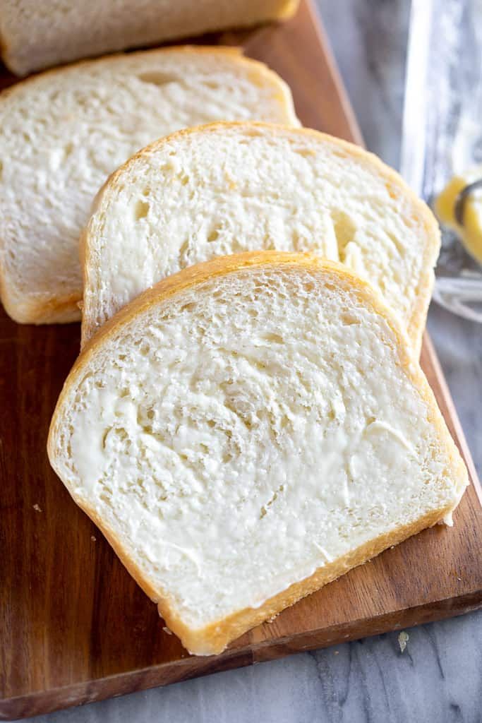 slices of white bread sitting on top of a wooden cutting board