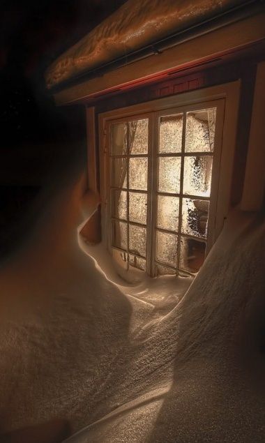 an open window in a dark room with snow on the ground and sunlight streaming through it