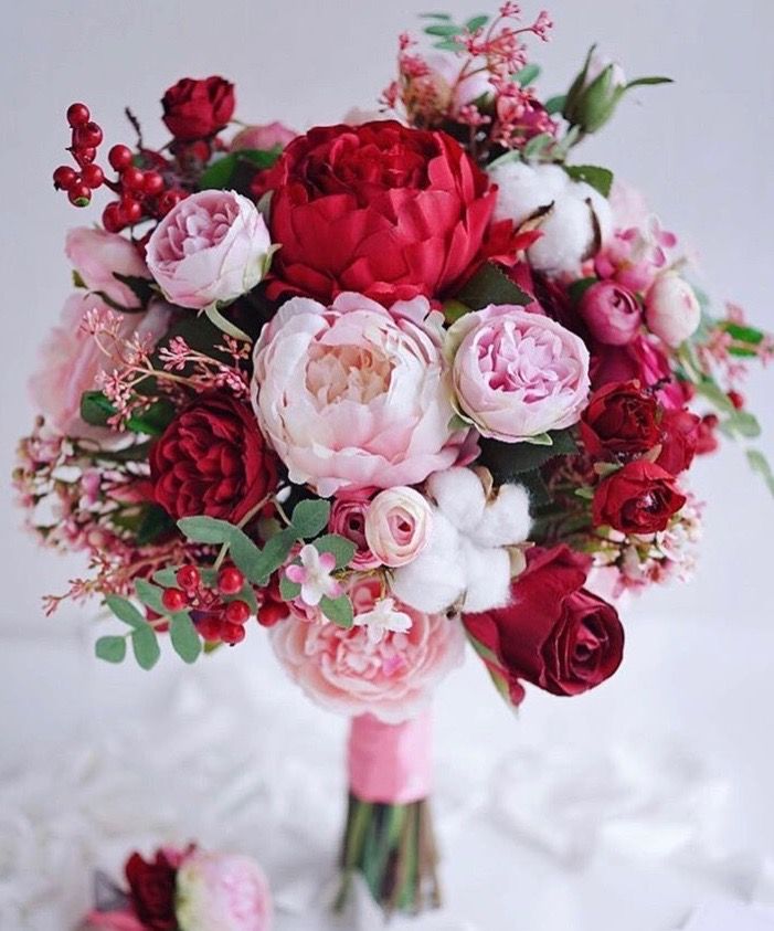 a bridal bouquet with pink and red flowers on a white tableclothed surface