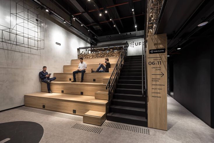 two men are sitting on the stairs in an office