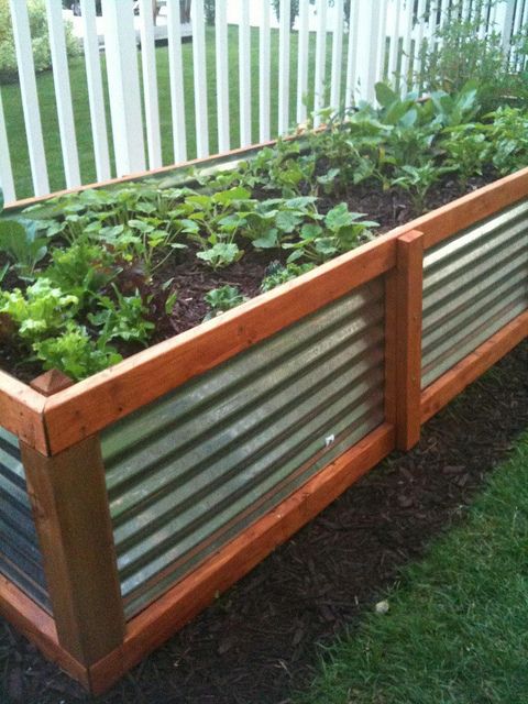 a wooden planter filled with lots of green plants