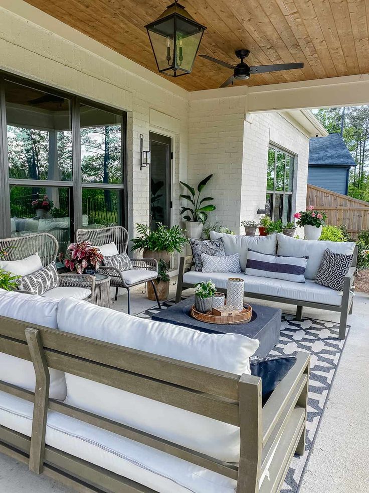 an outdoor living area with couches, tables and potted plants on the porch