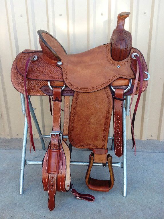 a saddle with a wooden horse head on the top and two reins attached to it