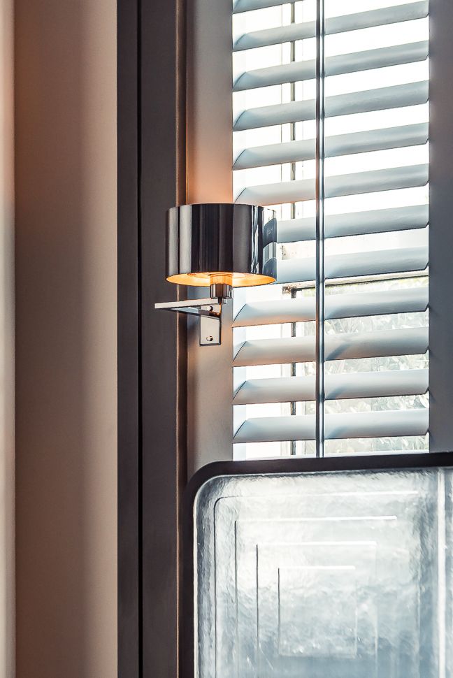 a lamp that is on the side of a wall next to a window with blinds