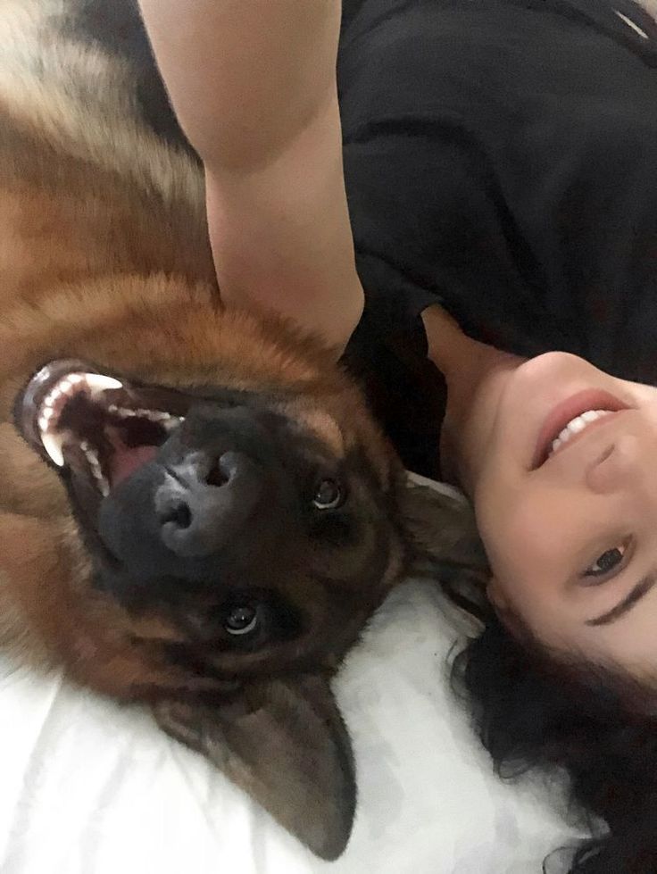 a woman laying next to a dog on top of a bed