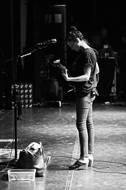 a man standing in front of a microphone while holding a guitar and looking at his cell phone