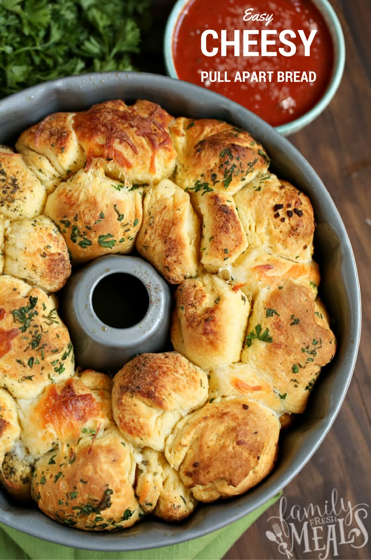 a pan filled with cheese pull apart bread on top of a green cloth next to some parsley