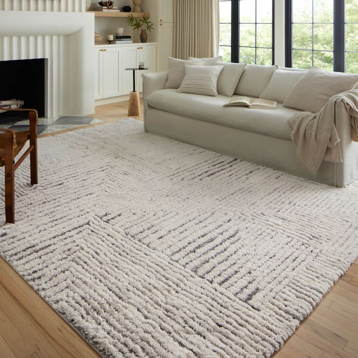 a living room with a white couch and rug in front of a fire place on the wall