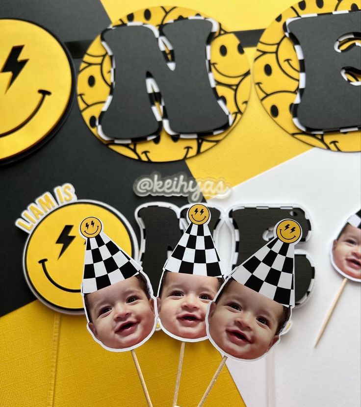 a cake topper with three pictures of babies on it and two candles in the shape of smiley faces