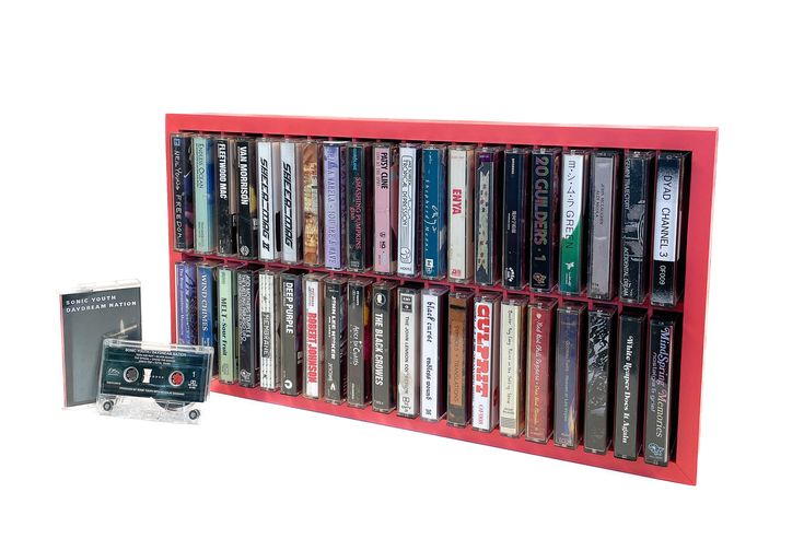 a red book shelf filled with lots of books next to a cd player and cassette recorder