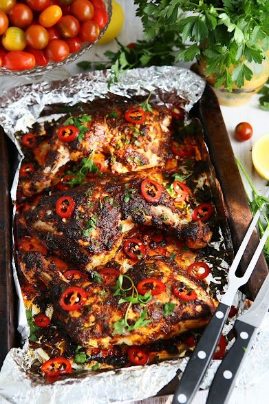 a pan filled with meat covered in tomatoes and peppers