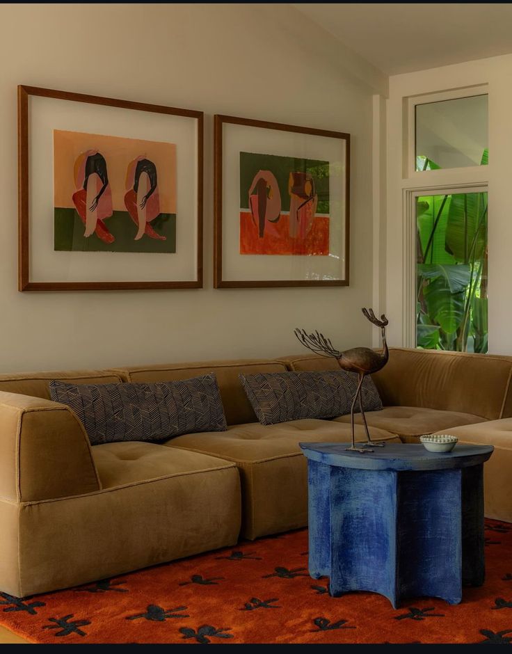 a living room filled with furniture and paintings on the wall above it's coffee table