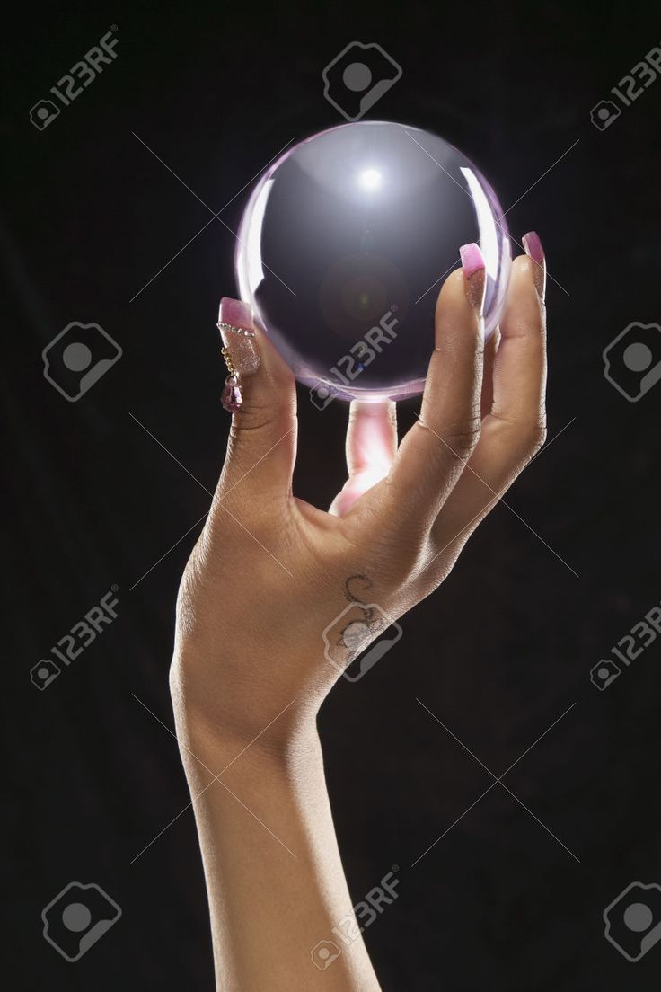 a woman's hand holding a crystal ball in the air