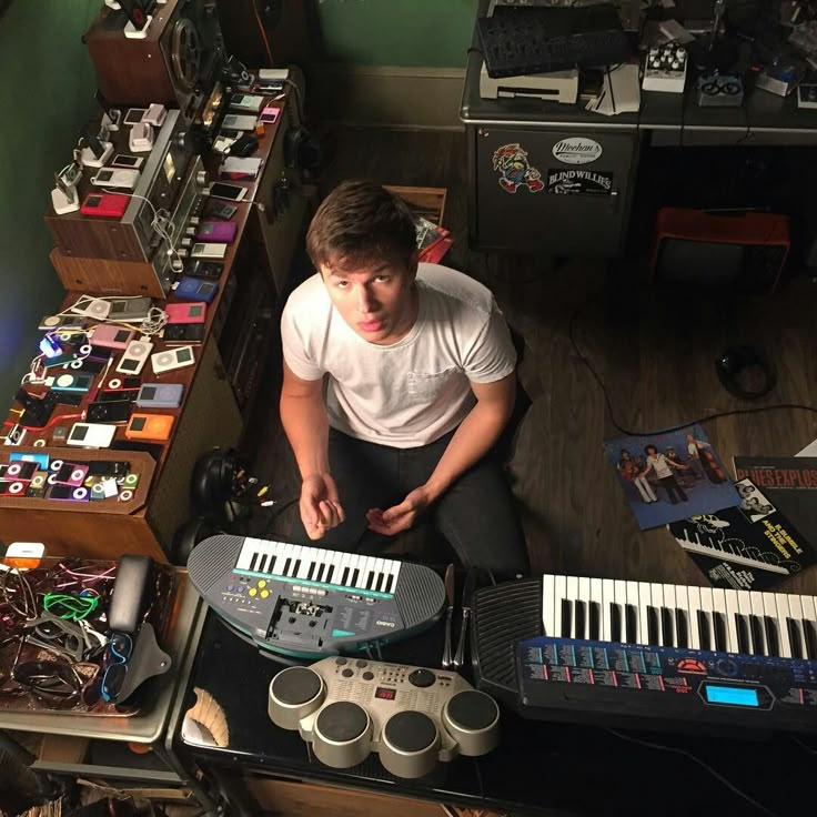 a man sitting on the floor surrounded by musical equipment