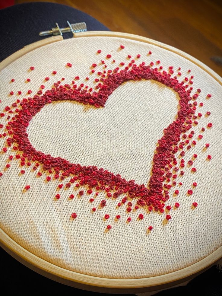 a heart is drawn on a piece of fabric with red thread in the shape of a cross stitch