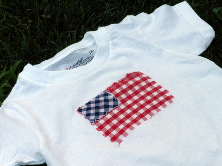 a white shirt with red and blue checkered patchwork on the chest sitting in grass