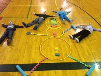 several children laying on the floor playing with toy hula hoops and toys in an indoor gym