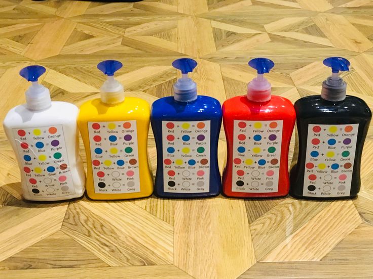 four different colored hand soaps are lined up on the floor