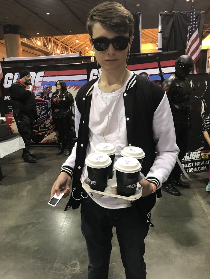 a young man holding two cups of coffee