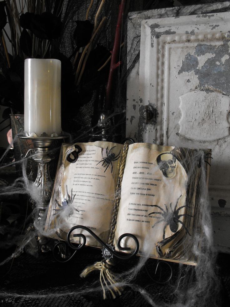 an open book sitting on top of a table next to a candle and spider web