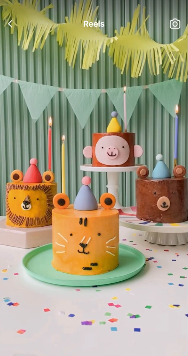 there are three cakes decorated with animals on top of each other and candles in the shape of monkeys