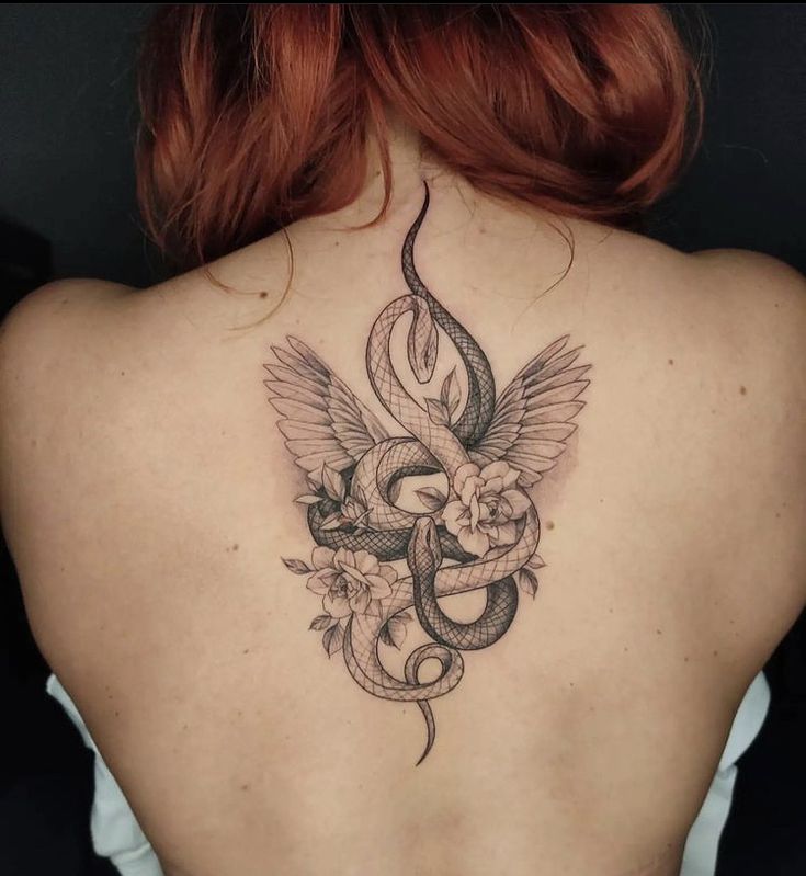 a woman's back with a snake and flowers tattoo on her left side ribcage