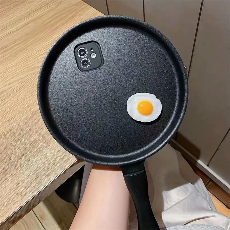 a person holding a frying pan with an egg on it