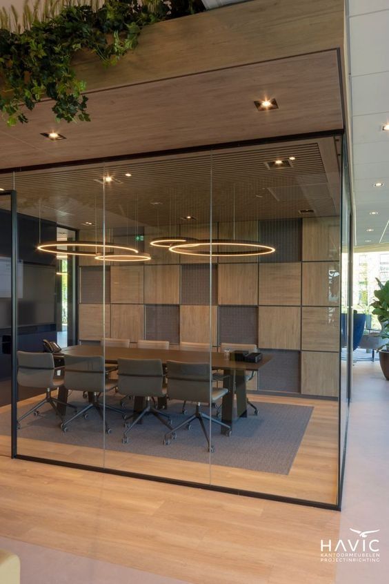 an office meeting room with glass walls and plants