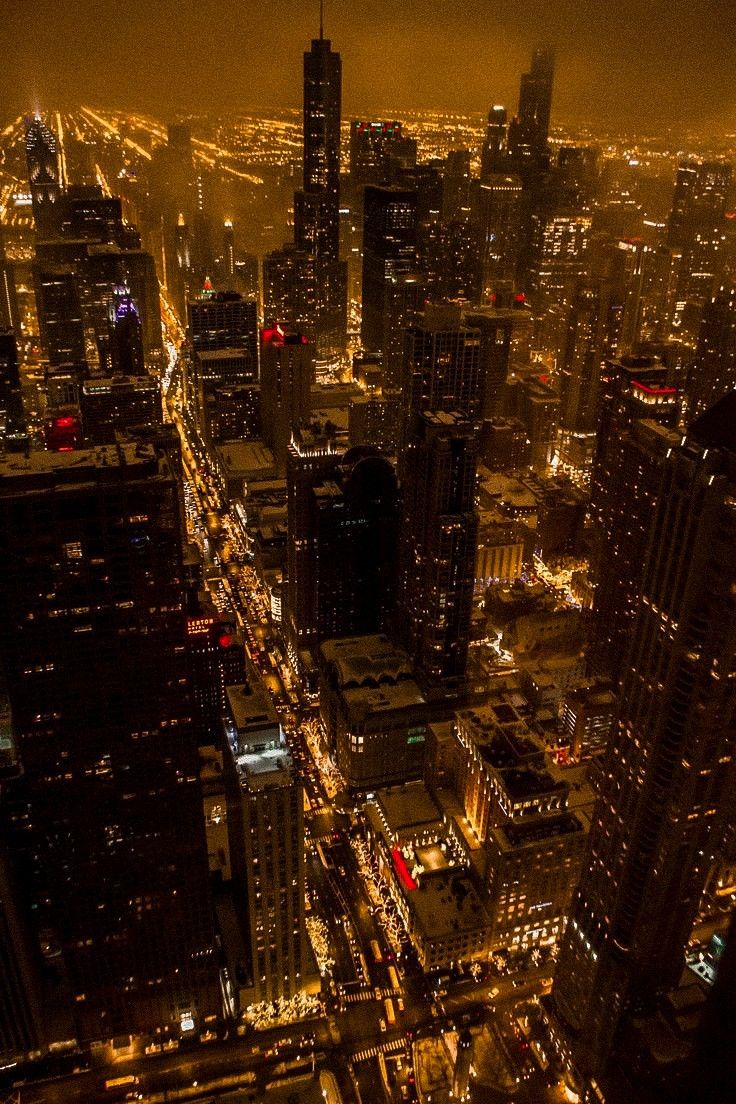 an aerial view of a city at night with lots of lights and skyscrapers in the background