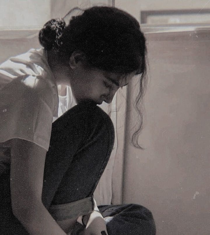 a woman sitting on the floor with her legs crossed and looking down at something in front of her