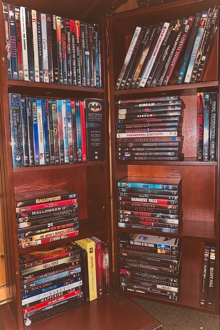 a wooden book case filled with lots of movies