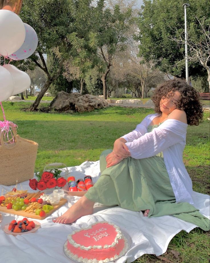 two women sitting on a blanket with cake and balloons