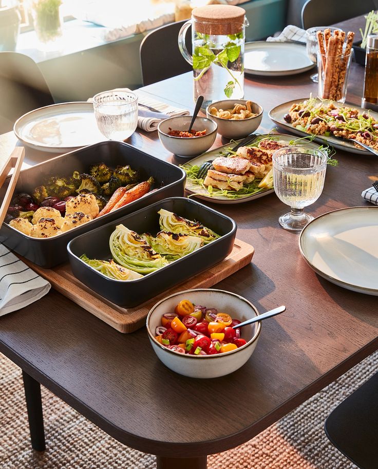 a wooden table topped with lots of plates and bowls filled with different types of food