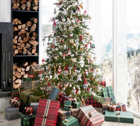 a christmas tree with presents under it in front of a fire place filled with logs