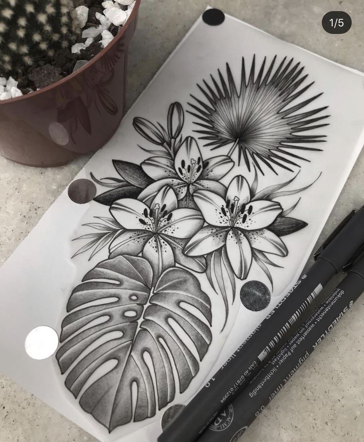 a black and white drawing of flowers next to a potted plant on a table