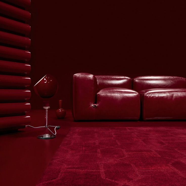 a red couch sitting on top of a rug in a living room next to a lamp