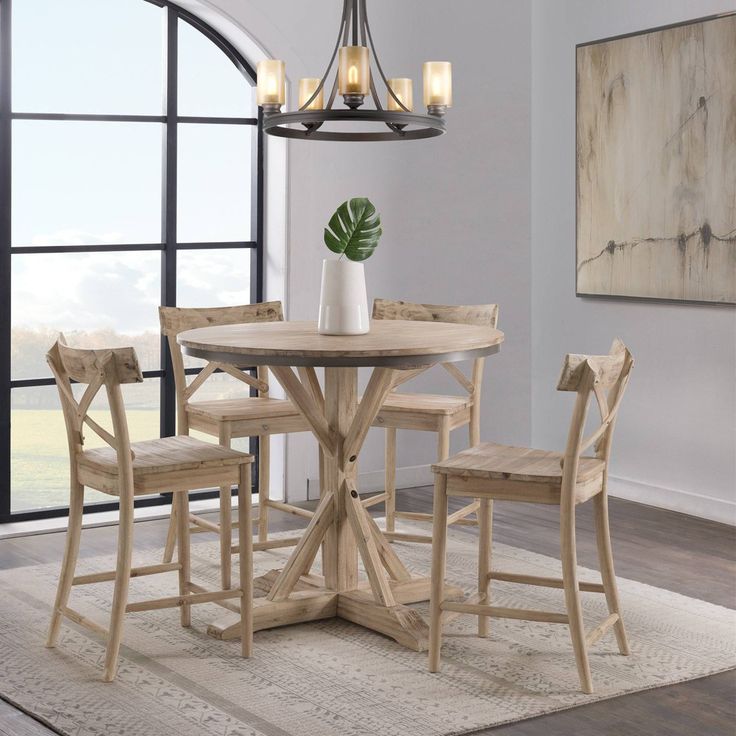 a dining room table with four chairs and a potted plant on the table in front of a large window