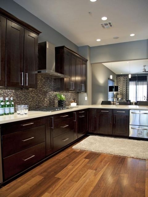 a kitchen with dark wood cabinets and white counter tops, along with stainless steel appliances