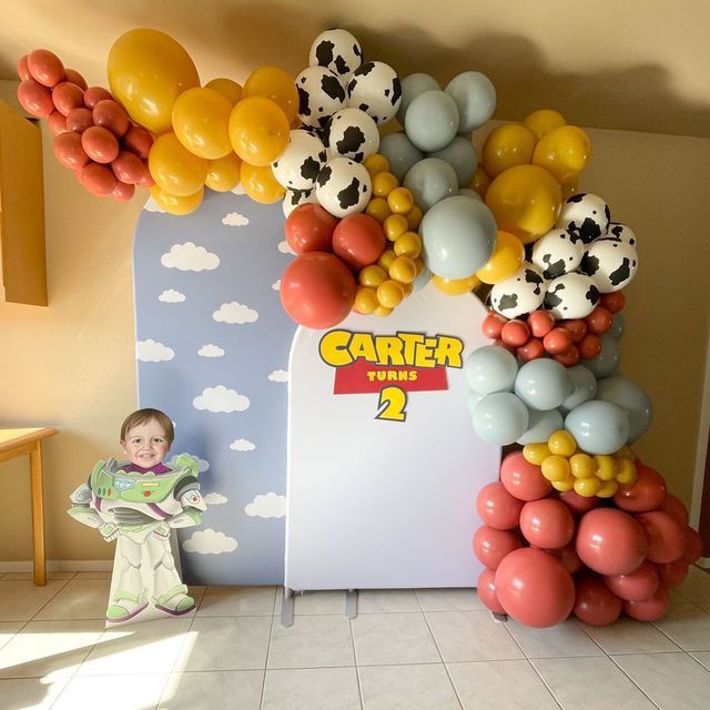 a child standing in front of a giant balloon arch with balloons on it's sides