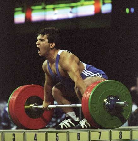 a man lifting a barbell on top of a weight scale