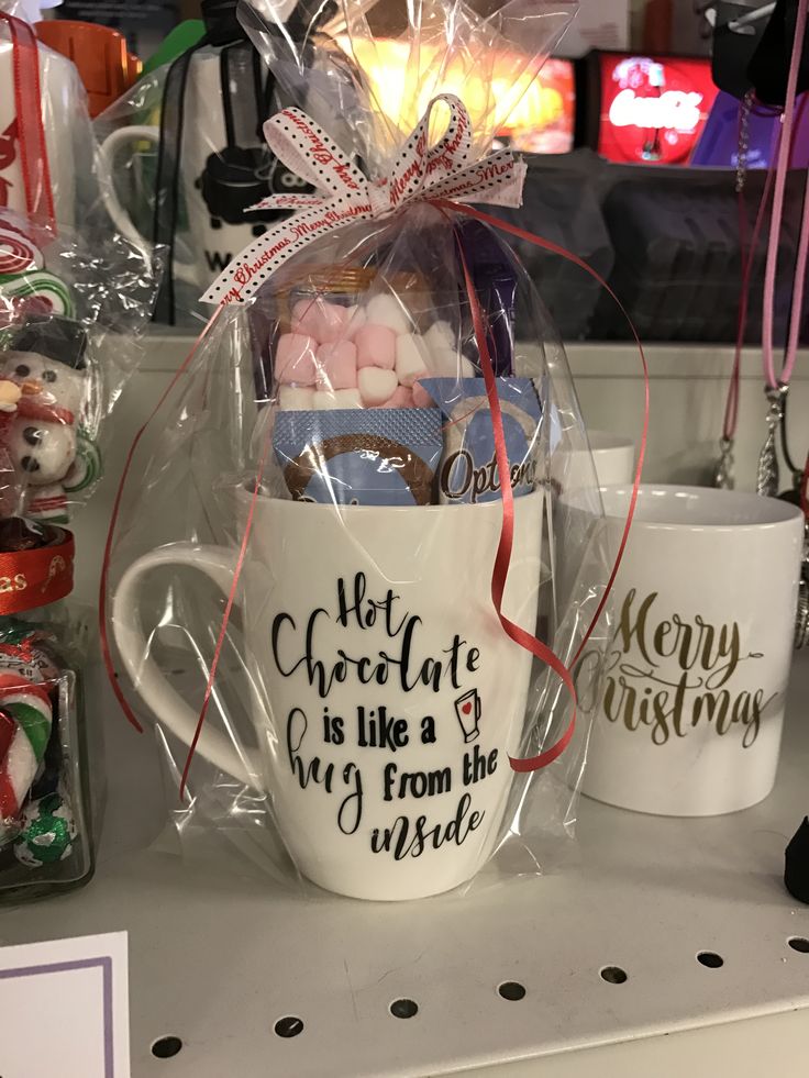 two mugs filled with candy and marshmallows sitting on a shelf in a store