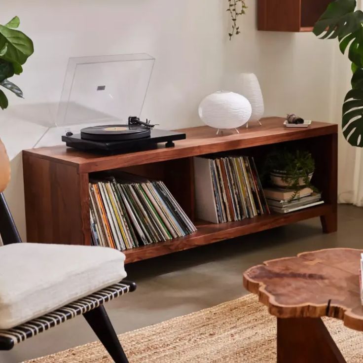 a record player sitting on top of a wooden shelf next to a table with records