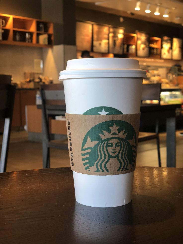 a starbucks cup sitting on top of a wooden table