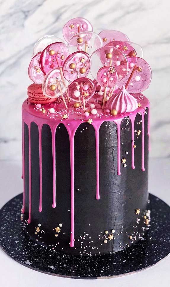 a black and pink cake with gold sprinkles on the top is covered in icing