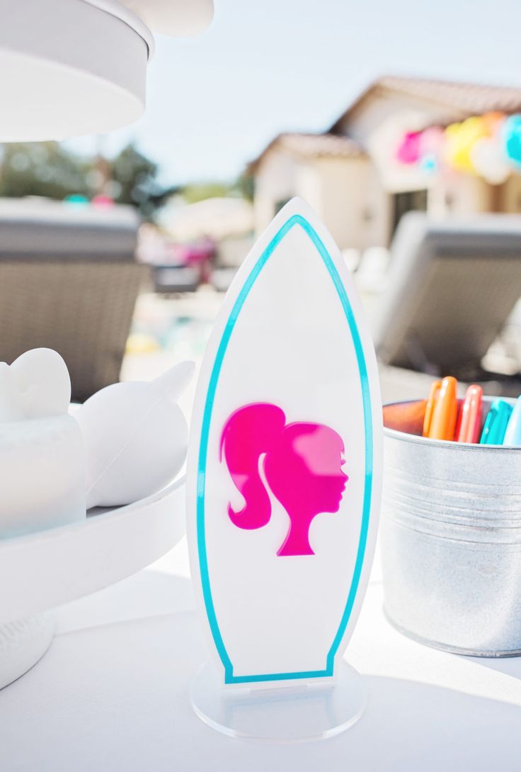 a surfboard shaped like a woman's head next to some markers and pens